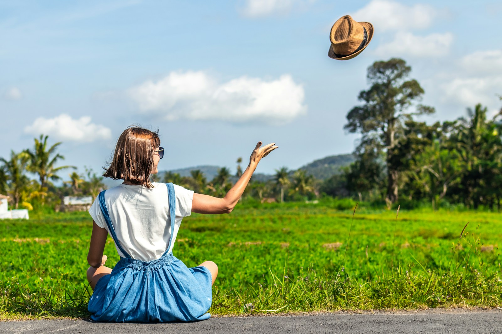 woman throwing up brown hat