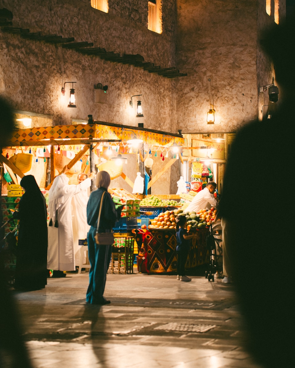People browsing fruit stalls at a nighttime market.