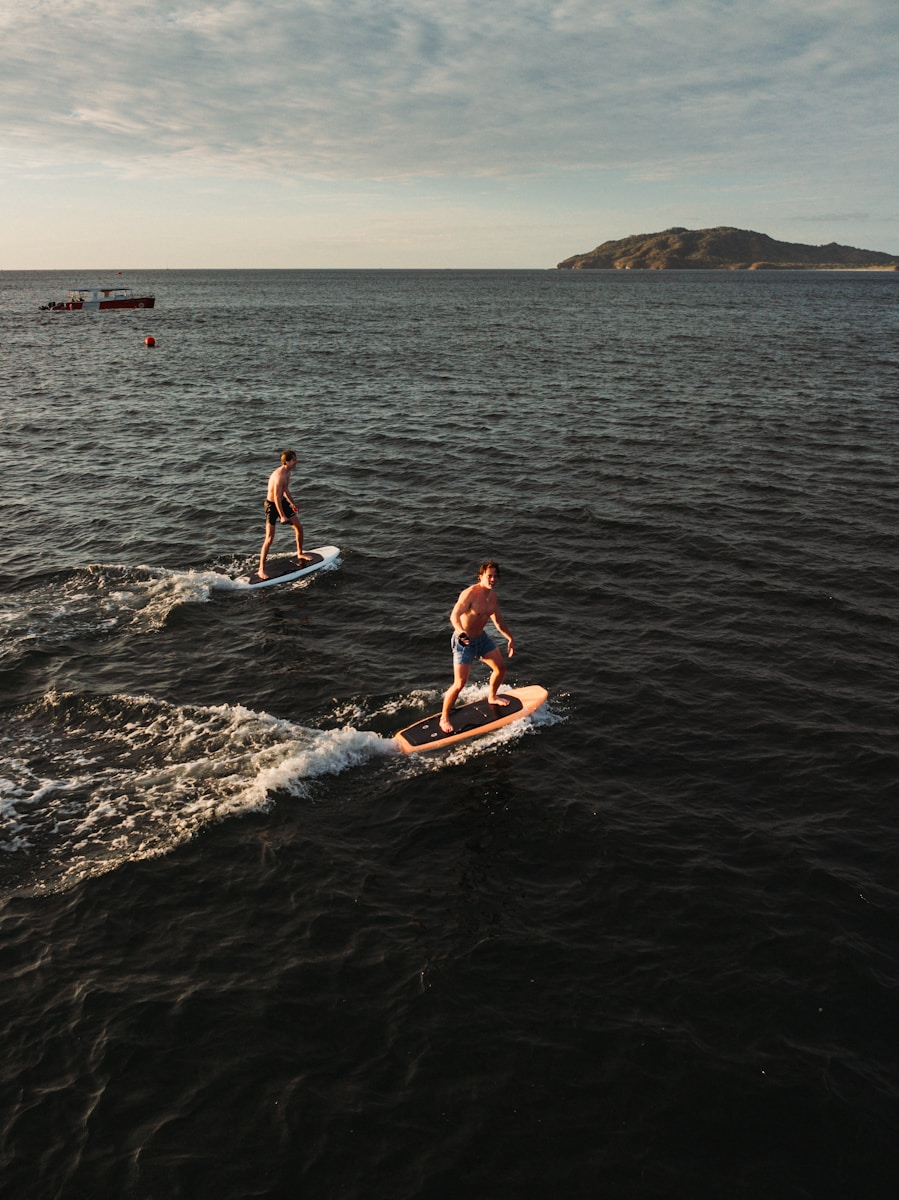Two men surfboarding on the ocean at sunset