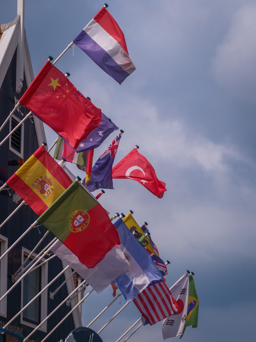 Various national flags flying against a cloudy sky.