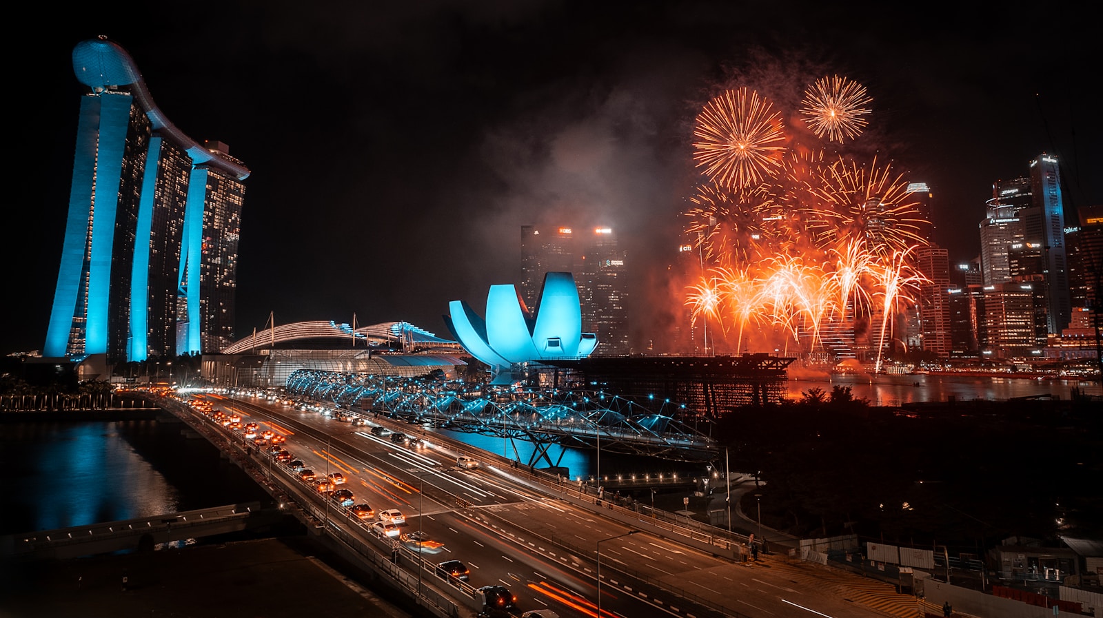 Fireworks explode over a city skyline at night.
