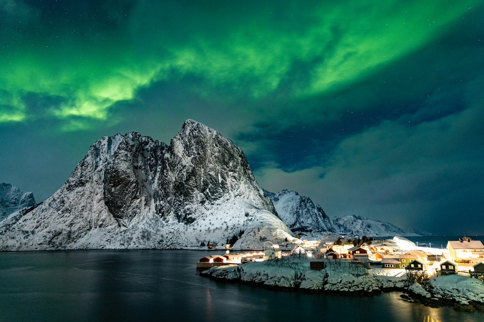 Northern lights over snow-capped mountains and village