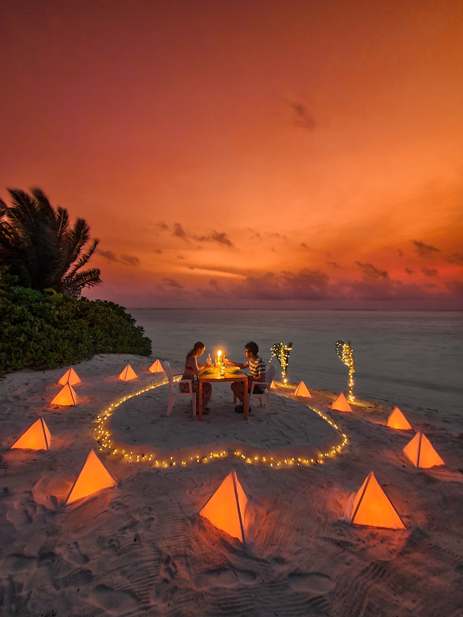 Couple having romantic dinner on beach at sunset.