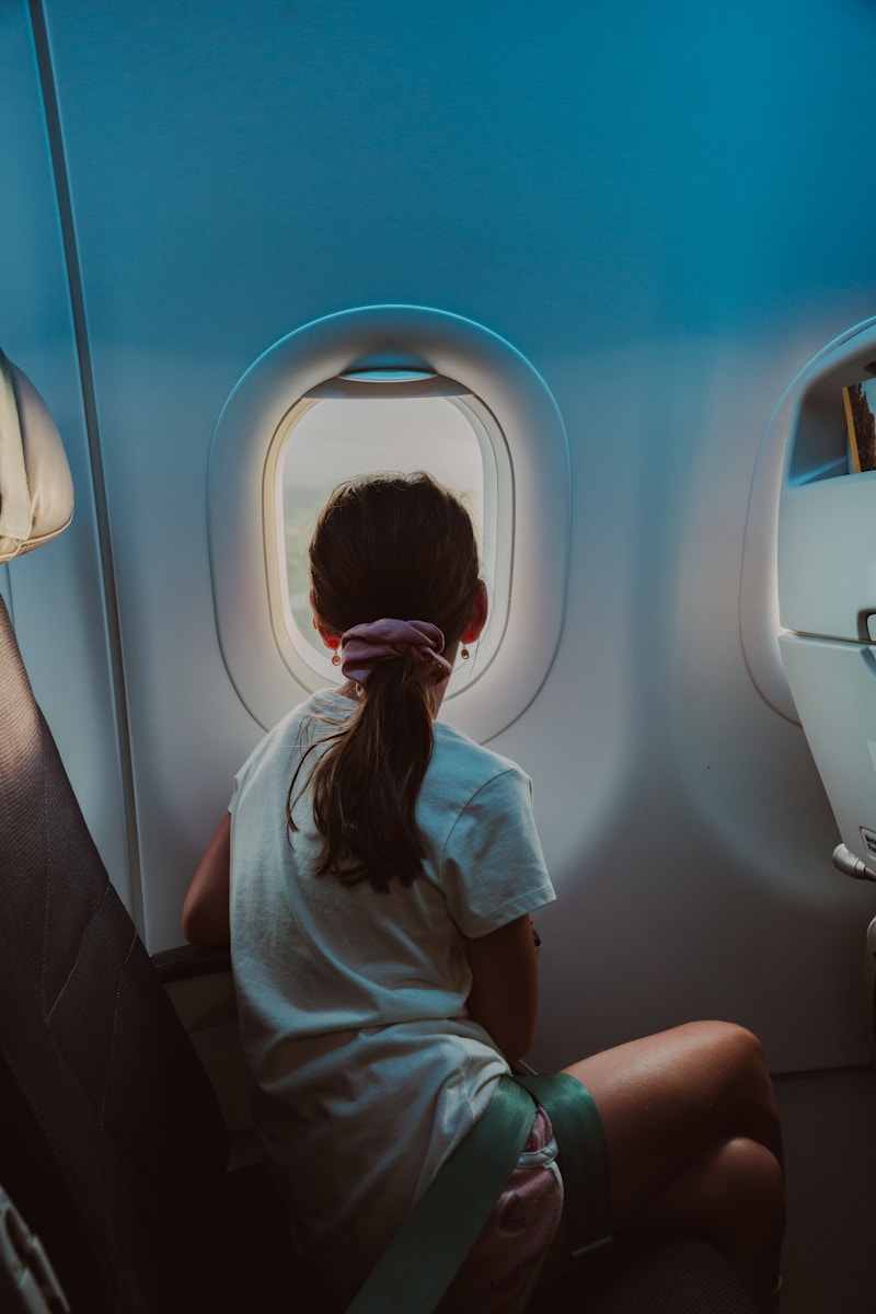 A woman sitting on an airplane seat looking out the window